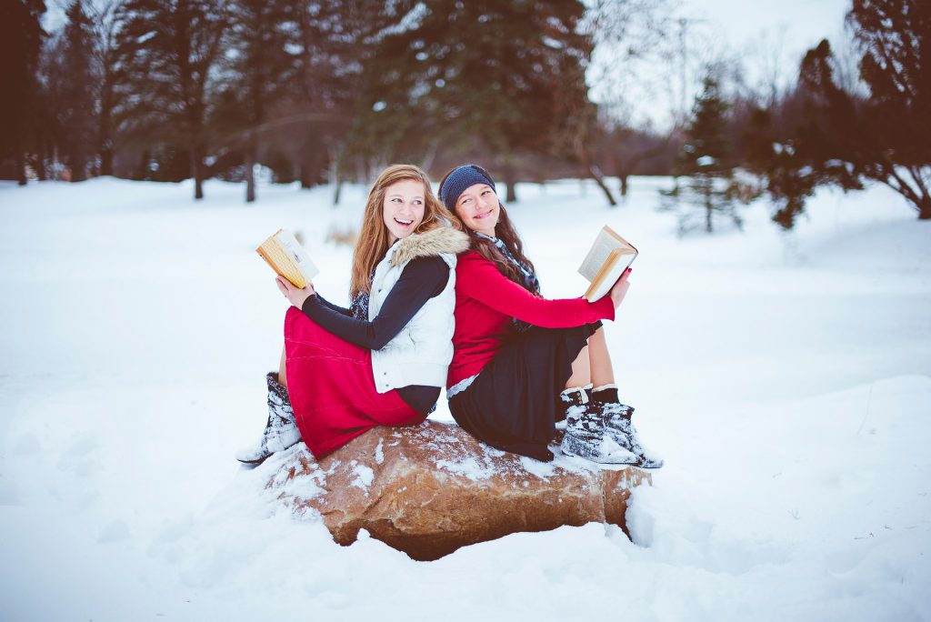 Two women reading in snow. 