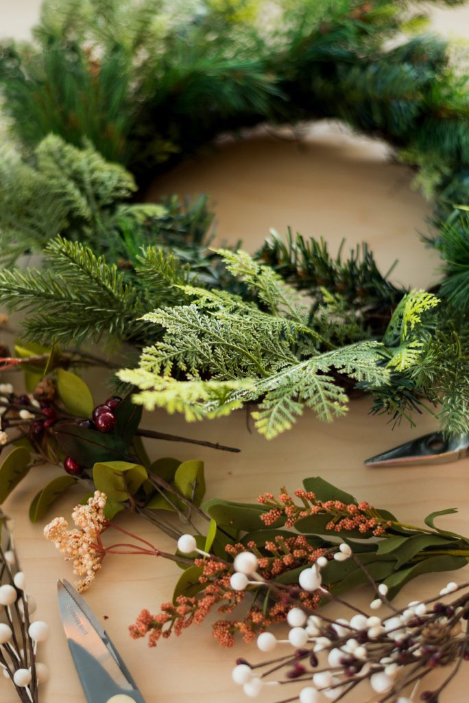 Making a wreath with greenery, flowers, and decorations. 